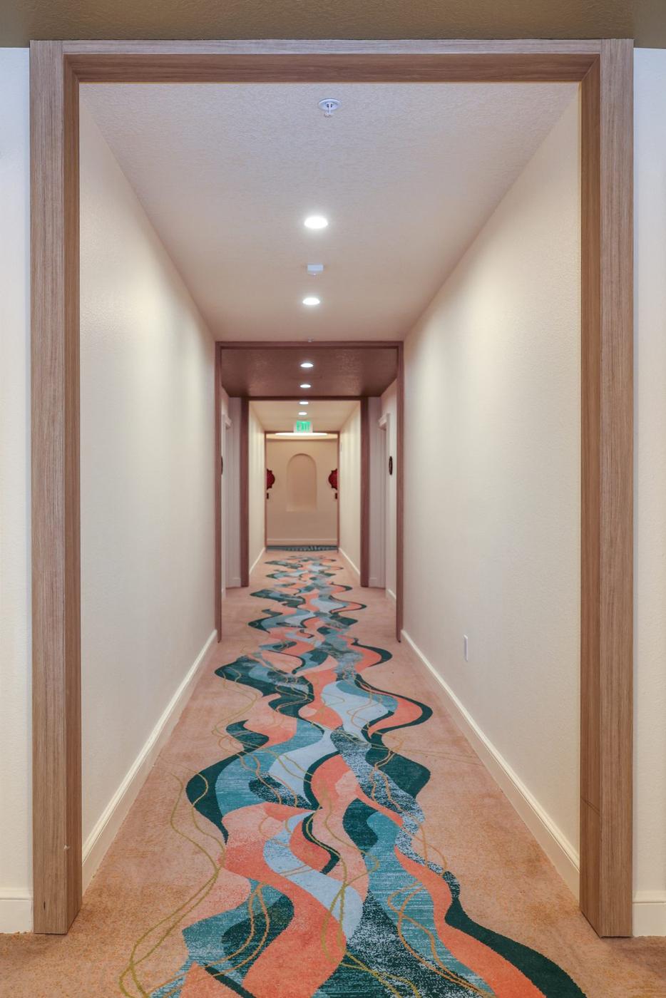 Long hotel corridor lined with wood-grain film doors